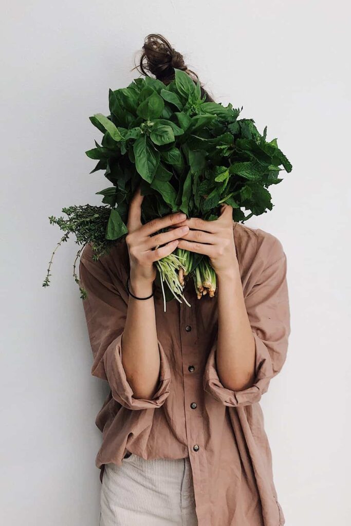 pexels-daria-shevtsova-3629537 - RIM Digital Person in a brown shirt hides their face behind a large bouquet of leafy green herbs.