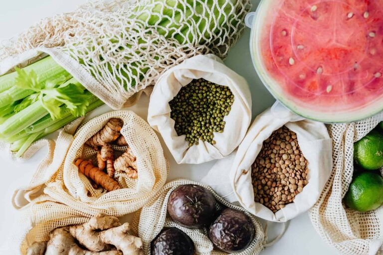 pexels-karolina-grabowska-5842510 - RIM Digital Assortment of fresh vegetables and legumes arranged in cloth bags and netting, with a watermelon on the right and green beans on the left