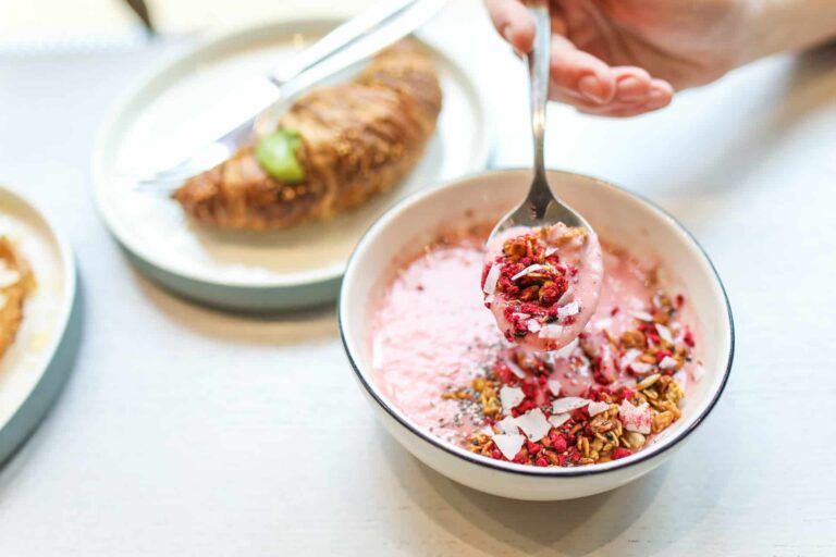 pexels-polina-tankilevitch-3872263 - RIM Digital Pink yogurt with granola and coconut flakes in a bowl, spoonful being lifted for a bite.