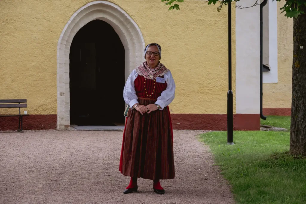 Kvinna bär Uppländs folkdräkt.