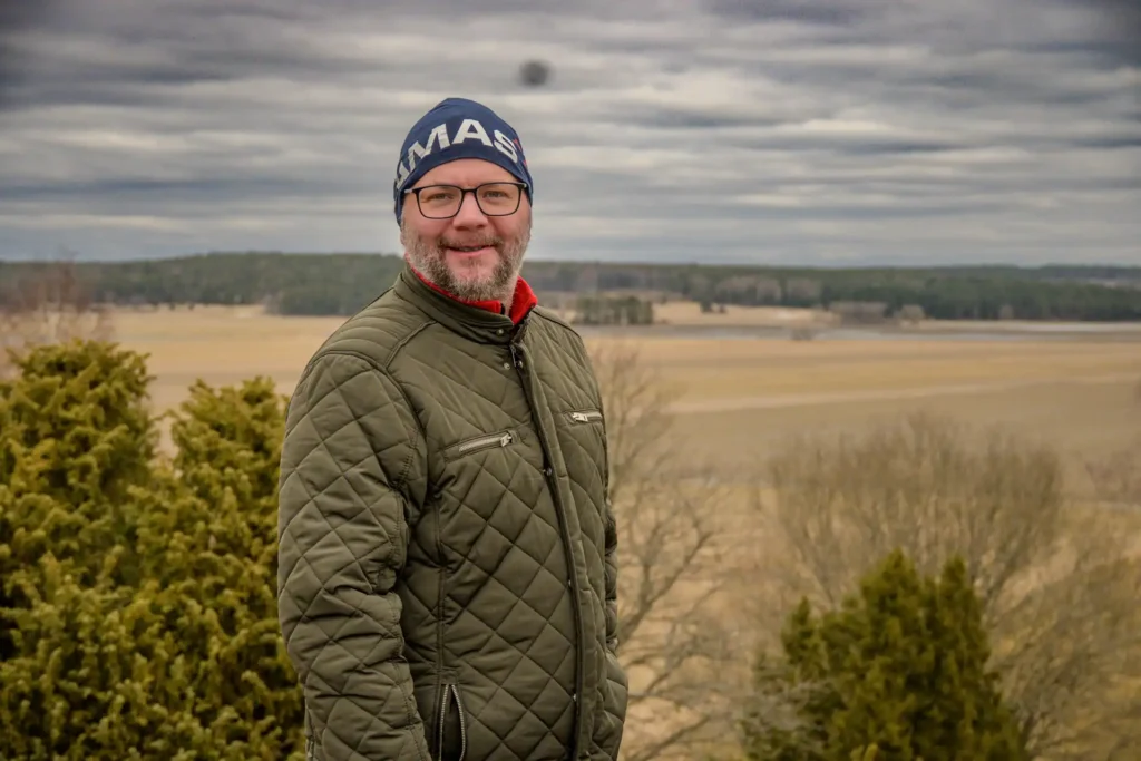 Leende man i grön jacka med Vånsjöbroåsen landskapet i bakgrunden.