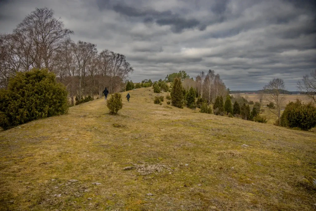 Vandrare på stigen längs Vånsjöbroåsen i Torstuna, med mörka moln ovanför det dramatiska landskapet utanför Enköping.